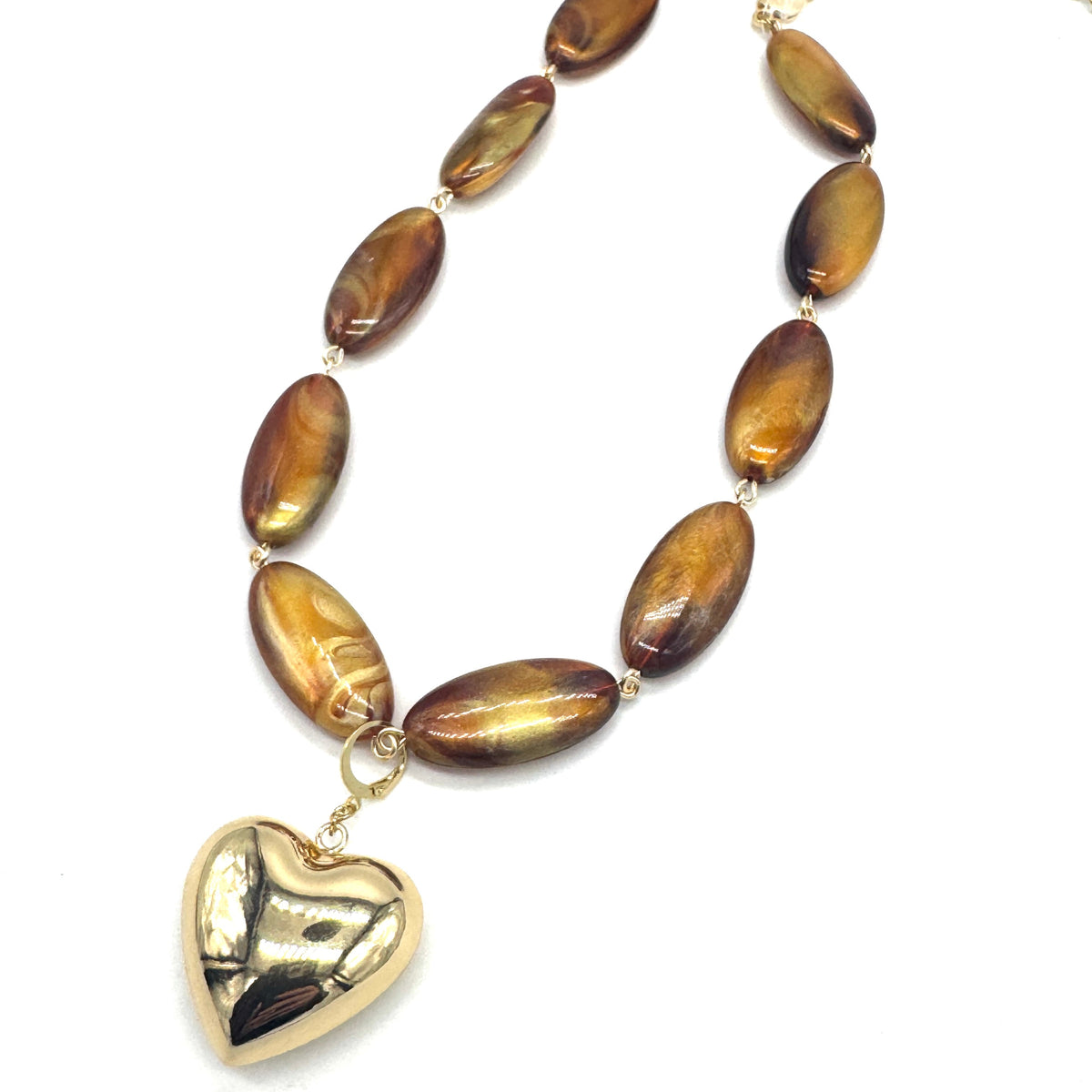 Necklace with brown oval beads and a gold heart pendant on a white background