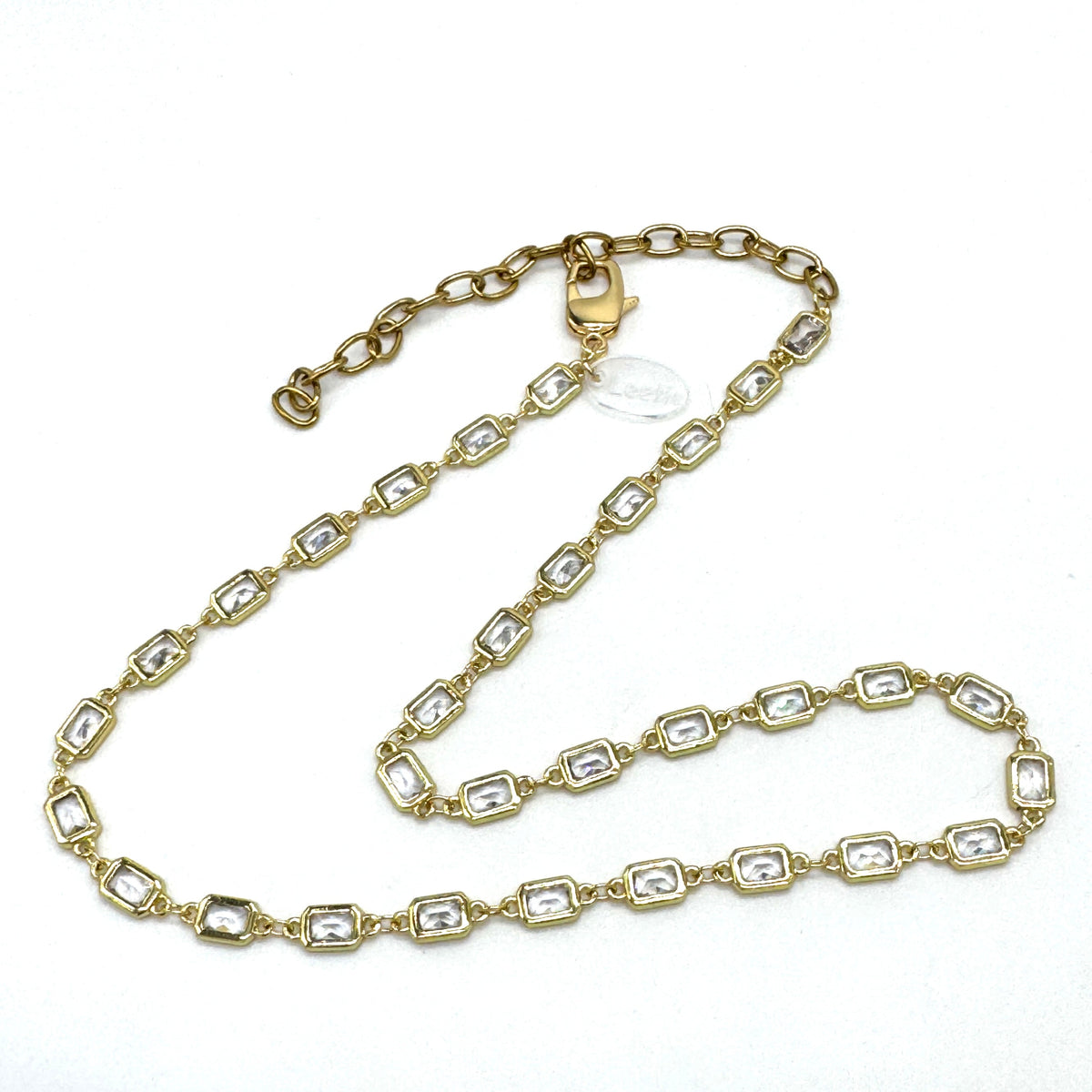 Gold chain necklace with clear stones on a white background