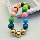 Colorful beaded necklace on a white surface with a white container in the background