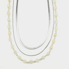 Three-strand silver chain and lucite beaded necklace on a white background