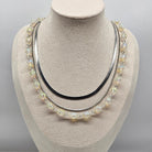Silver necklace with multiple strands on a mannequin bust against a gray background