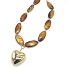 Necklace with brown oval beads and a gold heart pendant on a white background