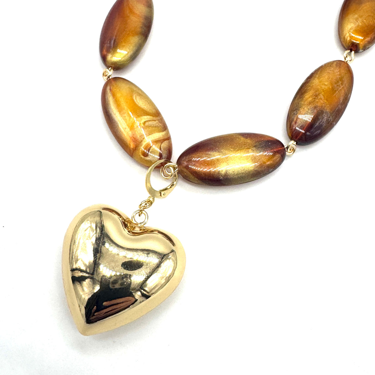 Necklace with brown oval beads and a gold heart pendant on a white background