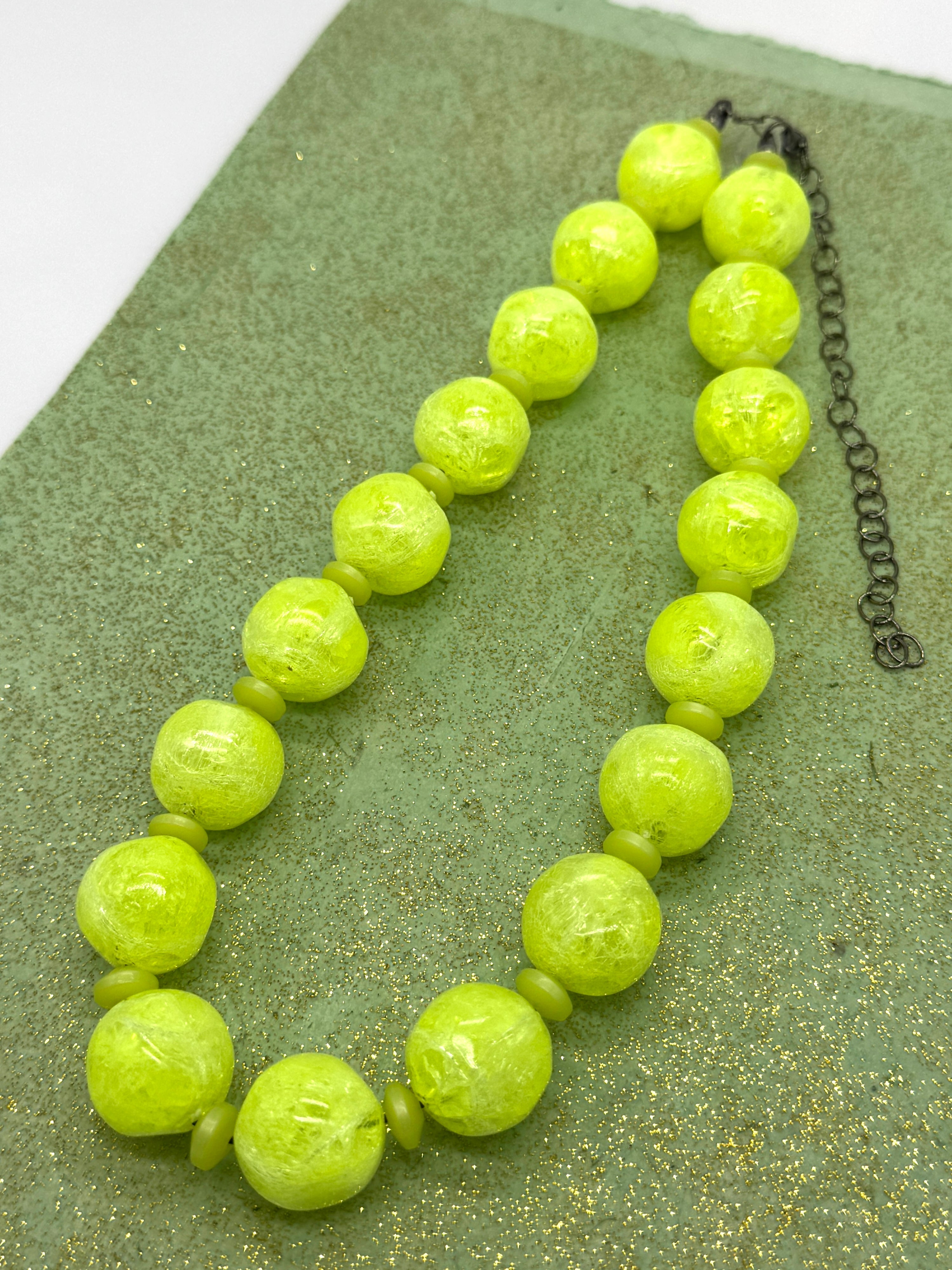 Necklace with bright yellow beads on a textured green surface