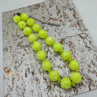 Neon yellow beaded necklace on a textured surface
