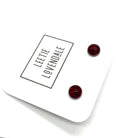 A pair of small round stud earrings in deep red resin, displayed on a white branded card that reads 'LEETIE LOVENDALE'.