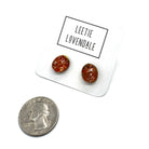 A pair of oval orange stud earrings on a white display card labeled 'LEETIE LOVENDALE,' with a U.S.